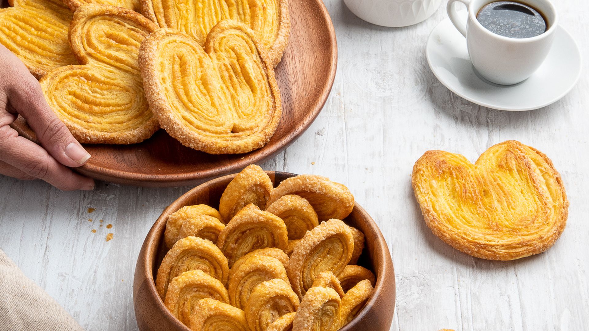 Corazones de hojaldre en plato de madera, con café y leche