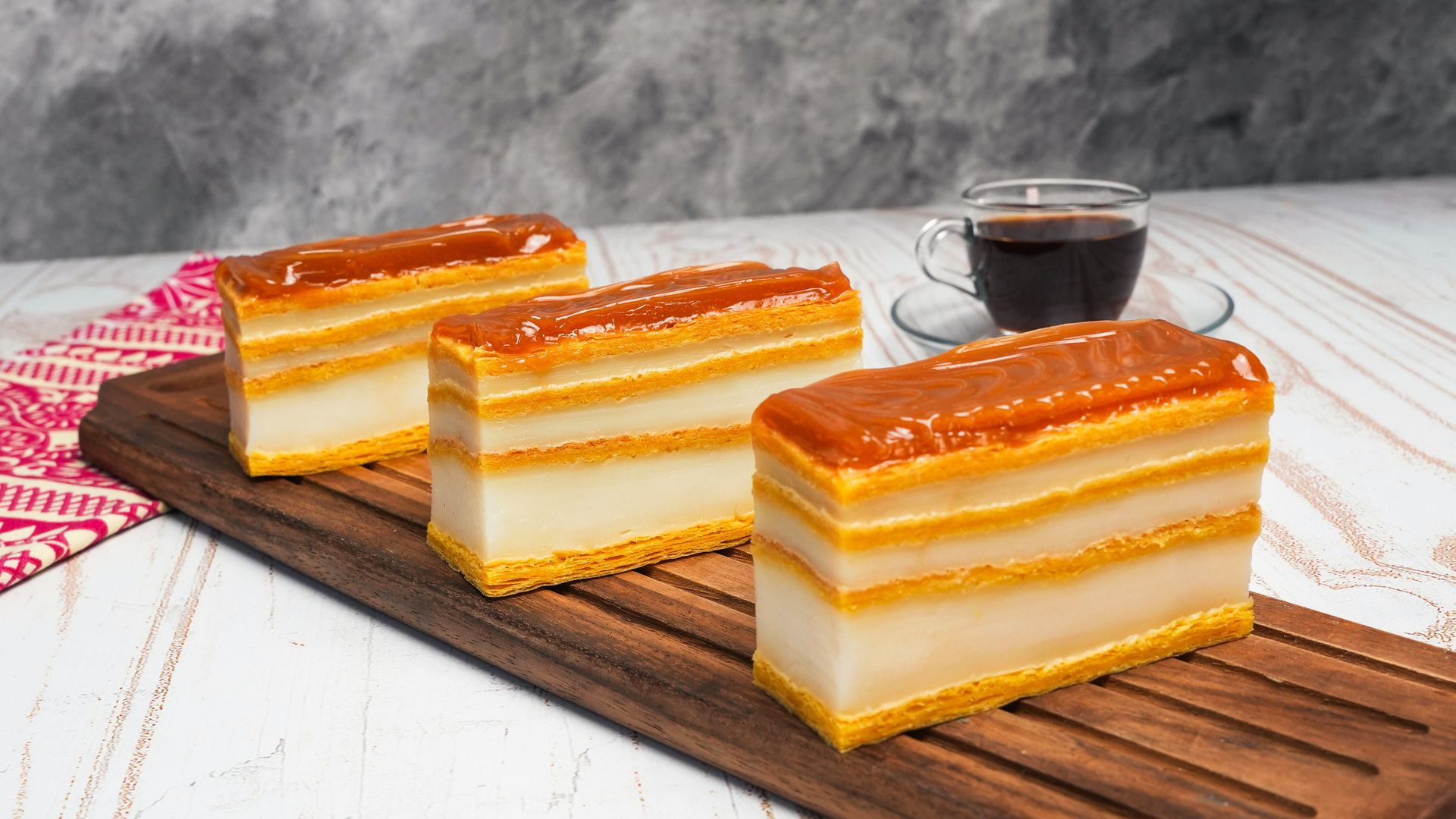 Milhojas en tabla de madera con capas de hojaldre, crema y arequipe